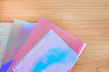 Colored notebooks iridescents with glitter on wooden desk for the return to school.