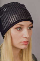 Portrait of a beautiful young girl in a stylish headdress with natural makeup on a gray background.