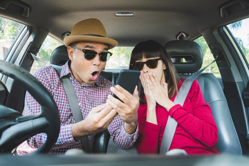 Couple asian man and woman sitting in car and looking at smartphone. Travel concept.