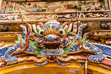 An ornate ceramic mosiac Chinese Lion above an arch in Hoàng thành (Imperial City) a walled citadel built in 1804 in Hue, Vietnam.
