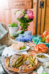 Dining table with different foods, snacks and flowers. Summer lunch in the open air. Seafood and vegetables.