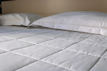 White bedding sheets in the hotel room closeup - Image - obrazy, fototapety, plakaty