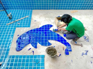 Tiled pool. The man hand while using spacer for installing tiles. construction work.Construction...