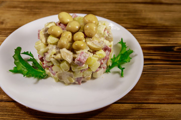Potato salad with marinated mushrooms, sausage, onion and mayonnaise on wooden table