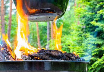 Lambent yellow hot flames of a fire of logs under a large suspended kettle with kettle goulash, cook