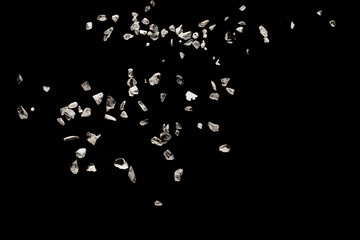 Split debris of stone exploding against black background.