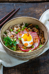 Ramen noodles with chicken, egg, mushrooms and radish sprinkeld with chili sauce and sesame seeds - high angle view