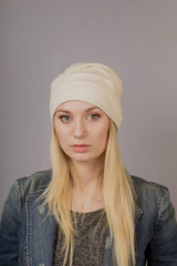 Portrait of a beautiful young girl in a stylish headdress with natural makeup on a gray background.