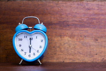 Heart shaped alarm clock on wooden background. Six O Clock