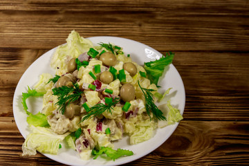 Potato salad with marinated mushrooms, eggs, red onion and mayonnaise on wooden table