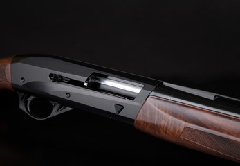 semi-automatic shotgun with a wooden butt and forearm on black background