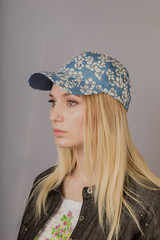 Portrait of a beautiful young girl in a stylish headdress with natural makeup on a gray background.