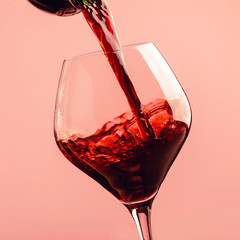 Französischer trockener Rotwein, gießt in Glas, trendiger rosafarbener Hintergrund, Platz für Text, selektiver Fokus