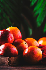 Juicy ripe shiny red bloody oranges in tray for making refreshing cocktail on rustic wooden table background, still life, selective focus