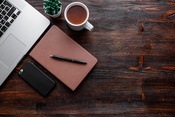 work space of a businessman. view from above . coffee black note and laptop on the desktop with black note. laptop on wooden background