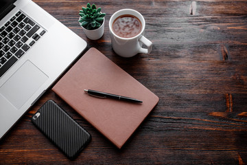 work space of a businessman. view from above . coffee black note and laptop on the desktop with black note. laptop on wooden background