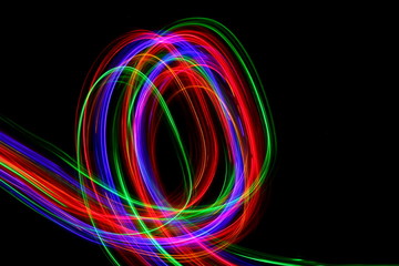 Long exposure, light painting photography. Multi color streaks and swirls of red, green and blue light against a black background.