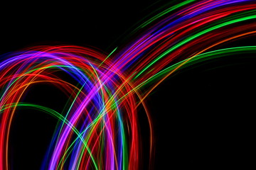 Long exposure, light painting photography. Multi color streaks and swirls of red, green and blue light against a black background.