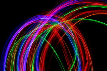 Long exposure, light painting photography. Multi color streaks and swirls of red, green and blue light against a black background.