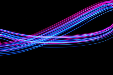 Long exposure, light painting photography.  Vibrant electric blue and neon pink streaks of colour against a black background