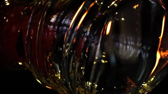 Glassblower in his workshop taking out rod with liquid glass and turning it. Close-up. Slow motion.