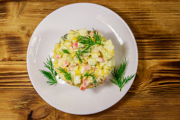 Salad with crab sticks, sweet corn, cucumber, eggs and mayonnaise on wooden table. Top view