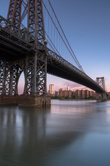 Williamsburg Bridge and  Financial district view from East River at sunrise with long exposure