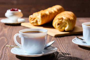 Rolled buns and coffee on wooden table in morning sunlight