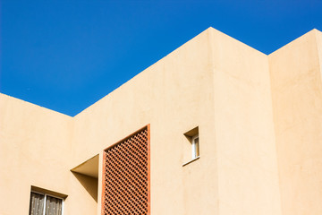 south cottage building geometrical shapes of lines and corners and windows on bright concrete wall, empty vivid blue sky 