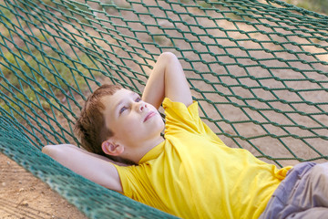 boy lying in a hammock and dream. the child resting in the garden