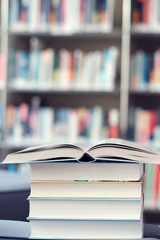 Open book on stack of books in a library.