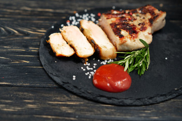 juicy piece of fried meat lies on a stone plate against a black wooden table