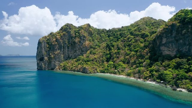 Limestone rocks of Lagen island. El Nido, Palawan, Philippines. Paradise tropical sandy Ipil Beach with azure turquoise sea water, coconut palm trees and local banca boats moored.