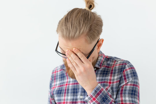 Emotions And People Concept - Young Hipster Bearded Man In Glasses And Shirt Is Confused And Looking Down