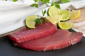 Raw red fresh tuna steaks on black chalkboard - image