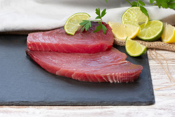 fresh tuna fillets accompanied by citrus and on black stone - image