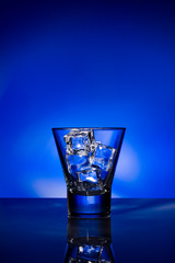 glass with ice cubes on blue background