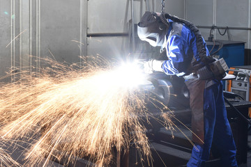 Schweißer in Schutzkleidung in der Industrie arbeitet // welder in industrial factory fpr metal...
