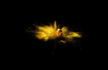 Bizarre forms of golden glitter powder paint explode in front of a black background to give off...