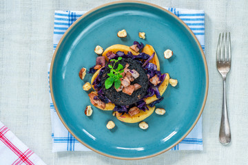 Warm salad of red cabbage, black pudding and apple with crispy bacon and crushed hazelnuts - overhead view