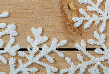 White snowflakes on a light wooden table. Christmas decoration background and copy space. Happy Merry Christmas and New year. 