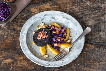 Warm salad of red cabbage, black pudding and apple with crispy bacon and crushed hazelnuts - overhead view
