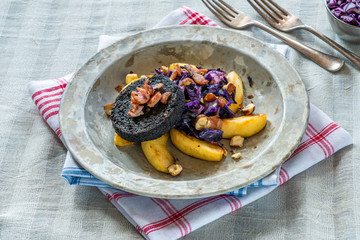 Warm salad of red cabbage, black pudding and apple with crispy bacon and crushed hazelnuts.