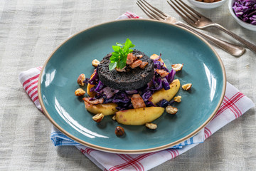 Warm salad of red cabbage, black pudding and apple with crispy bacon and crushed hazelnuts.