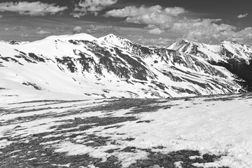 Black and white photography of beautiful high altitude blue alpine lake with snow capped peaks, Rocky Mountains, Colorado