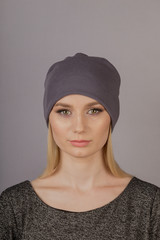 Beautiful girl with natural make-up in a headdress on a gray background.