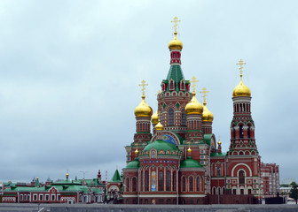 Fototapeta na wymiar beautiful red brick Church with Golden domes on blue sky background