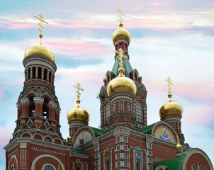 Fototapeta na wymiar beautiful red brick Church with Golden domes on blue sky background