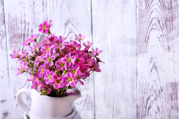 Heap of white crockery and pink field flowers on top. Interior idea