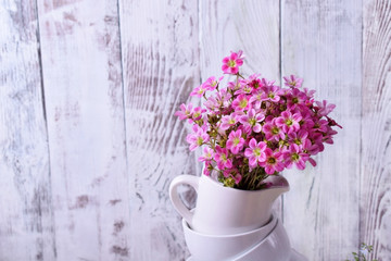 Heap of white crockery and pink field flowers on top. Interior idea